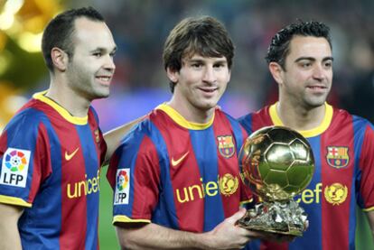 Andrés Iniesta, Leo Messi y Xavi Hernández posan con el Balón de Oro, en el estadio del Nou Camp, el 12 de enero de 2011.