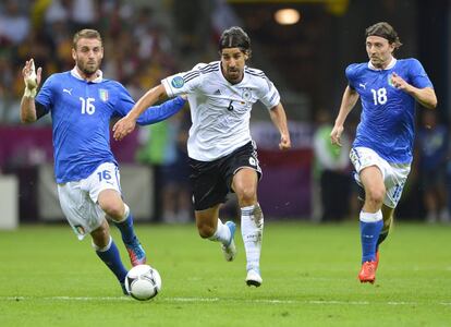 Sami Khedira y los italinos Daniele De Rossi y Riccardo Montolivo corren tras el balón.