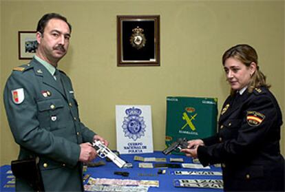 Un sargento de la Guardia Civil de Guadalajara y la jefa de prensa de la policía muestran las armas incautadas.