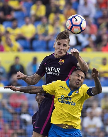 El defensa del Barcelona Lucas Digne remata de cabeza el balón superando al delantero de Las Palmas Jonathan Viera durante el partido.