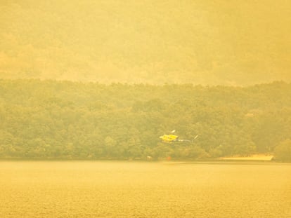 Un helicóptero recoge agua en el Lago de Sanabria, cubierto de humo, este miércoles.