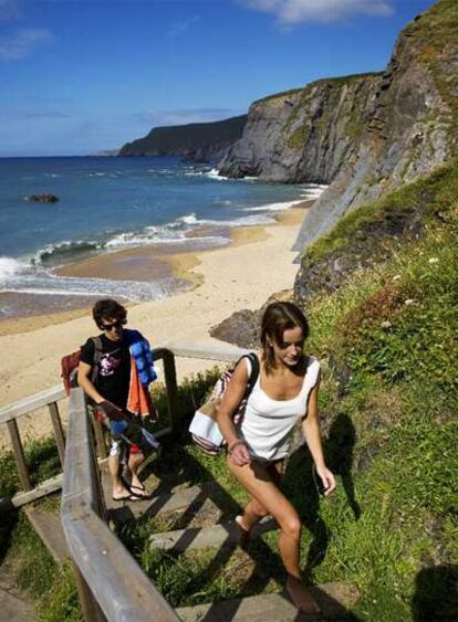 Dos jóvenes bañistas regresan tras una jornada en la playa de Picón.