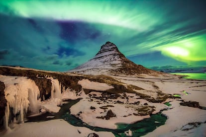 Luzes no céu pertencentes a uma aurora boreal iluminam a Montanha da Igreja, em Kirjuffell (Islândia). Trata-se de um lugar muito popular entre os turistas que desejam assistir a esse fenômeno natural.