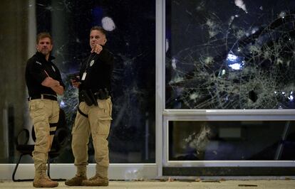 Dos miembros de las fuerzas policiales, ante una cristalera dañada de la Corte Suprema.
