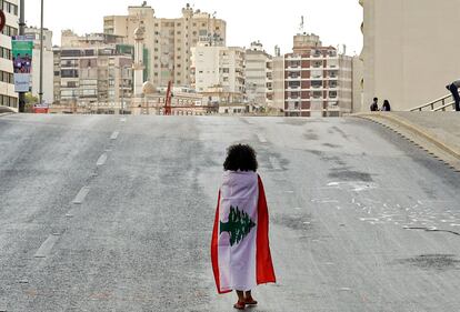 El país de los cedros, como se conoce a Líbano, está al borde del colapso económico debido a décadas de malas recetas financieras y de una corrupción crónica entre los políticos que han dejado el 60% de la riqueza nacional en manos de 2.000 familias. En la foto, una niña camina envuelta en una bandera nacional a lo largo de la carretera Fuad Chehab, en el centro de la capital Beirut.