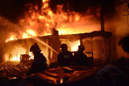 Los equipos de rescate temen que aumente el número de fallecidos, según ha declarado Ali Ahmed, el jefe del servicio nacional de bomberos. En la imagen, bomberos y vecinos ayudan a apagar el fuego en uno de los edificios.