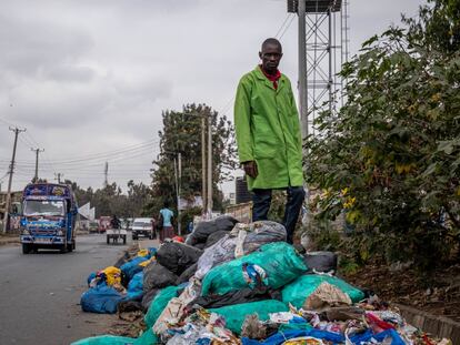 Evans Otieno posa encima de plásticos y basura en descomposición en el asentamiento chabolista de Dandora, Nairobi.