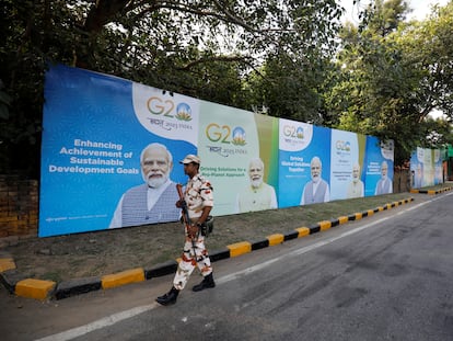 Un miembro de las fuerzas de seguridad patrulla una calle de Nueva Delhi delante de una serie de cartéles que retratan al primer ministro de la India, Narendra Modi.