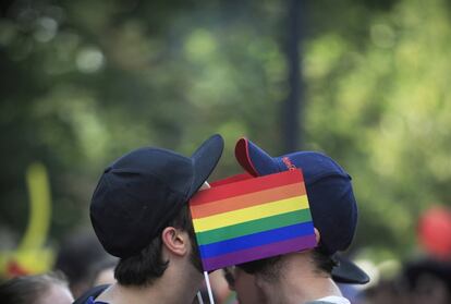 Dos hombres cubren sus rostros con banderas de arco iris durante un desfile del orgullo gay en Bucarest, Rumania.