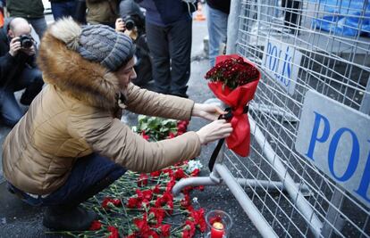 Una mujer coloca un ramo de flores en un valla frente a la discoteca Reina.