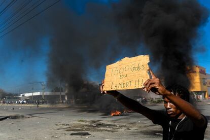 Un hombre muestra un cartel en el que se lee "1.500 gourdes", unos 15 dólares, que es la cantidad que reclama un grupo de manifestantes para el salario mínimo en Puerto Príncipe (Haití).