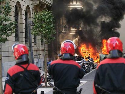 Tres <i>ertzainas</i> observan unos contenedores ardiendo en la calle Hondarribia, en el centro de San Sebastián, ayer por la tarde.

JESÚS URIARTE