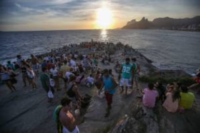 Un grupo de personas observa la puesta del sol en la piedra de Arpoador en Río de Janeiro (Brasil). La piedra de Arpoador, que divide las playas de Copacabana e Ipanema en Río de Janeiro, es el lugar más concurrido de esta ciudad brasileña para divisar la puesta de sol.