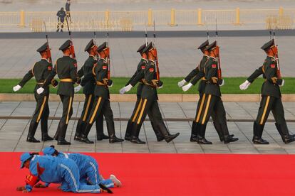 Un grupo de trabajadores limpian la alfombra roja antes de una ceremonia de colocación de coronas en el Monumento a los Héroes del Pueblo en la Plaza Tiananmen en el 70º aniversario de la fundación de la República Popular de China, en Beijing.