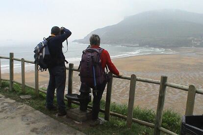 Dos peregrinos contemplan la playa de la Arena, en Zierbena, en el tramo de la costa del Camino de Santiago.