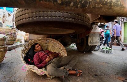 EPA5457. GUWAHATI (INDIA), 23/10/2018.- Un conductor descansa bajo su camión durante la huelga convocada en Assam (India), el 23 de octubre de 2018. 46 organizaciones mantuvieron un paro de 12 horas en el estado para protestar contra la tentativa del centro de aprobar el proyecto de ley que modifica la Ley de ciudadanía de 1955.