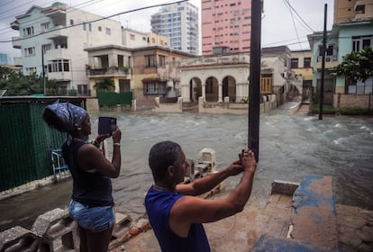 Una pareja toma fotografías de las calles anegadas de agua en La Habana.