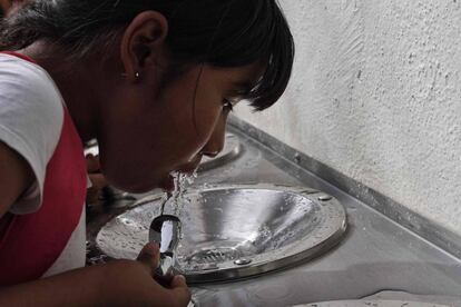 Una niña bebe agua de un bebedero en Querétaro.