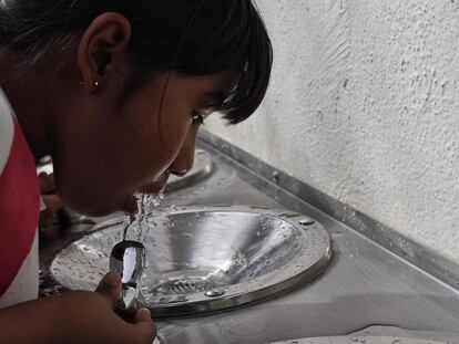 Una niña bebe agua de un bebedero en Querétaro.