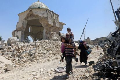 Una familia de civiles iraquíes pasa por delante de la mezquita en ruinas de Grand al-Nuri después de huir de la ciudad vieja de Mosul, Iraq.