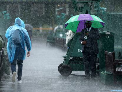 Un empleado de Wimbledon se protege de la lluvia.