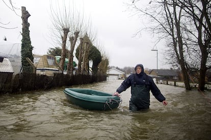 Un hombre tira de una pequeña barca tras las inundaciones cerca de Shepperton, al sur de Londres. El temporal de lluvia que azota al Reino Unido ha provocado las peores inundaciones en décadas y ha situado el nivel de las aguas del Támesis en el más alto en más de 30 años, mientras nuevas precipitaciones amenazan con empeorar la situación.