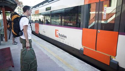 Uns usuaris esperen un tren del servei de Rodalies Renfe.