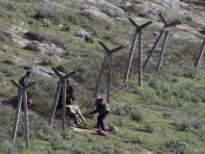 Un grupo de sirios pasan por debajo de una valla alambrada para entrar en territorio turco cerca de Reyhanli, ayer.