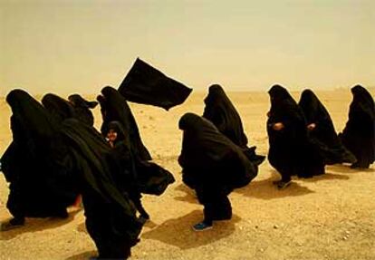 Mujeres iraquíes chiíes caminan en peregrinación rumbo a la ciudad santa de Kerbala a través de una tormenta de arena en el desierto.