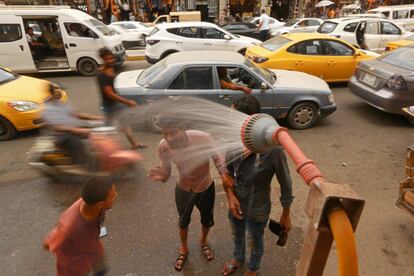 La gente se refresca del calor del verano en una ducha pública de Bagdad (Irak), donde las temperaturas han superado los 40 grados.