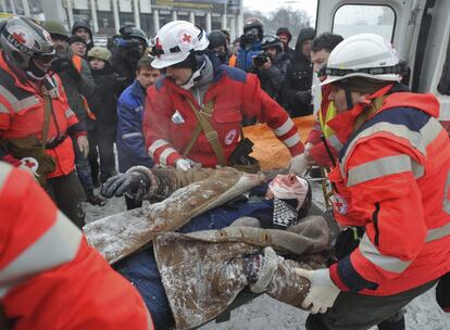 Miembros de los servicios de emergencia de la Cruz Roja ayudan a un herido durante los enfrentamientos entre policía y manifestantes en el centro de Kiev (Ucrania), 22 de enero de 2014. 