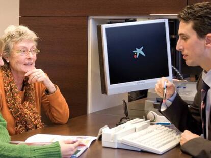 Unos clientes de CaixaBank conversan con un empleado en una oficina de la entidad.
