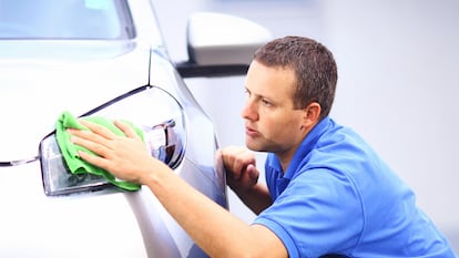 Un hombre puliendo los faros de  su coche.