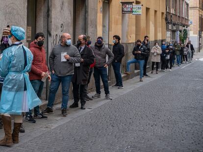 Personal sanitario atiende a personas haciendo cola para realizarse una PCR frente al centro de salud Universidad en Malasaña, Madrid.