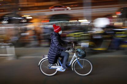 Una mujer se protege de la contaminación con una máscara mientras monta en bicicleta en plena hora punta en Pekín.