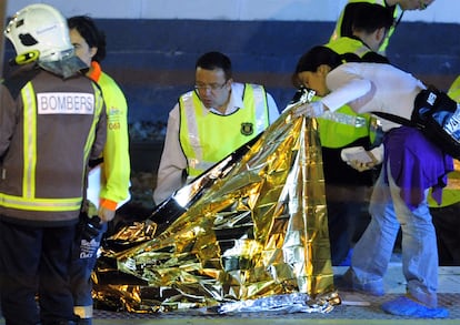 Miembros de la policía y de los equipos de rescate inspeccionan uno de los cadáveres de la tragedia de Castelldefells.