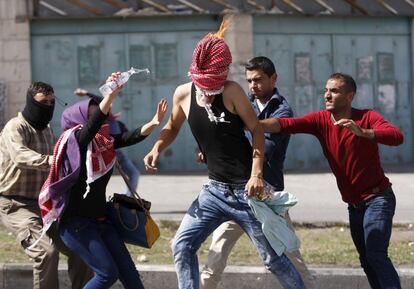 Un grupo de jóvenes intentan apagar las llamas del pañuelo que cubre la cabeza de un palestino tras lanzar un cóctel molotov en la ciudad de Hebrón.