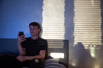 Un adolescente usa su 'smartphone' en su habitación.