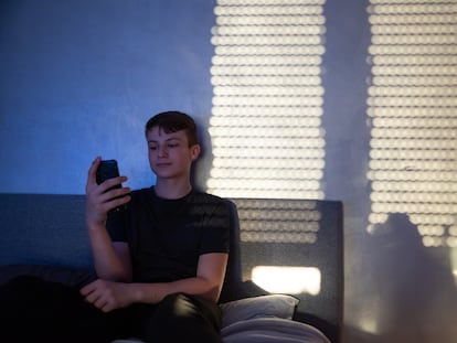 Un adolescente usa su 'smartphone' en su habitación.