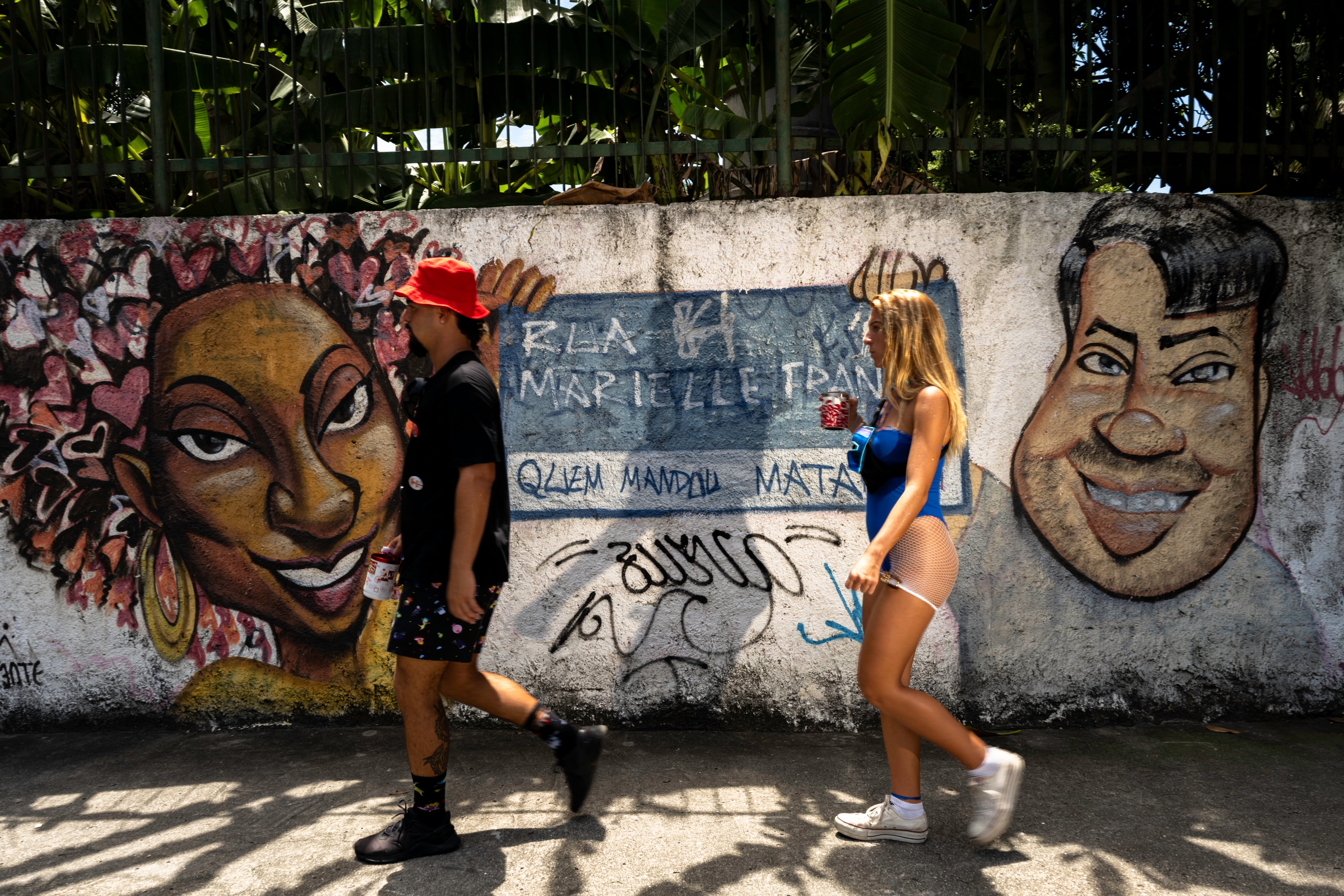 Dos personas disfrazadas pasan, el martes de Carnaval, ante el grafiti que recuerda a Marielle y a Anderson, su conductor, en la calle donde los asesinaron.