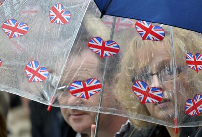 Dos espectadores observan el torneo mientras evitan la lluvia con su paraguas, uno de los elementos esenciales para el público.