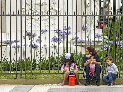 Mulher com seus dois filhos pede ajuda em uma rua de Buenos Aires, no dia 4 de dezembro.