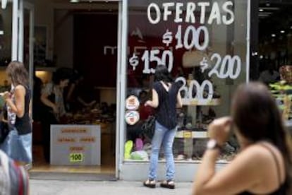 Una mujer observa una vitrina que anuncia ofertas en calazado, en el centro de Buenos Aires (Argentina). EFE/Archivo