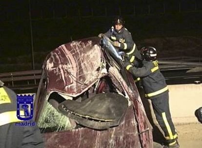 Los bomberos trabajan para retirar el coche incrustado entre la mediana de la autovía madrileña.