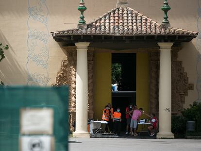 Un trabajador de la Cruz Roja toma la temperatura a una persona en la puerta de un pabellón para sin techo de Barcelona.