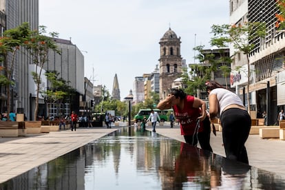 Personas tocan el agua y se refrescan en el monumento El Palomar de Luis Barragán