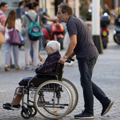 DVD1237(23/10/2024). Sevilla. Un hombre desplaza en silla de ruedas a una mujer mayor el pasado mes de octubre en Sevilla. FOTO: PACO PUENTES (EL PAÍS)