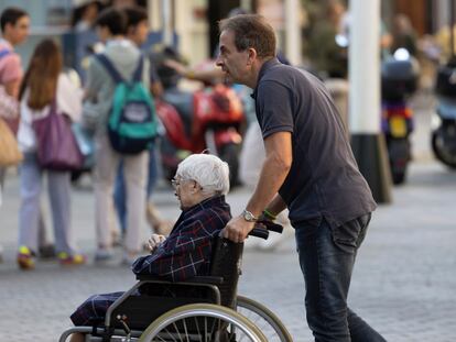 DVD1237(23/10/2024). Sevilla. Un hombre desplaza en silla de ruedas a una mujer mayor el pasado mes de octubre en Sevilla. FOTO: PACO PUENTES (EL PAÍS)
