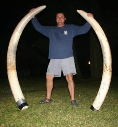 El cazador posa con dos colmillos de elefante de una de sus presas.