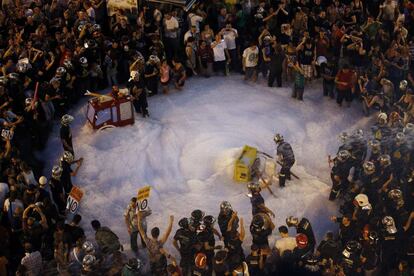 Un grupo de bomberos tira espuma en la Puerta del Sol de Madrid, en medio de las protestas contra los recortes a las que se han sumado miles de personas